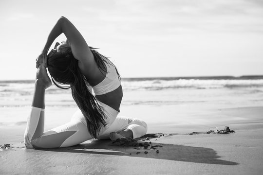 Woman doing yoga on beach, black and white