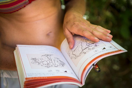 Mid section of a female climber looking at a guidebook