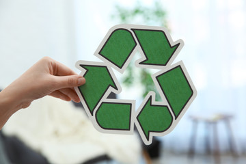 Woman holding recycling symbol on blurred background, closeup