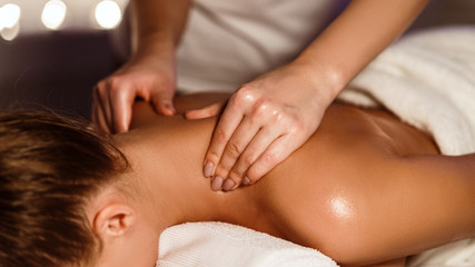 Fototapeta na wymiar Girl enjoying therapeutic neck massage in spa