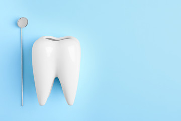 Dentist mirror and tooth shaped holder on color background, top view with space for text