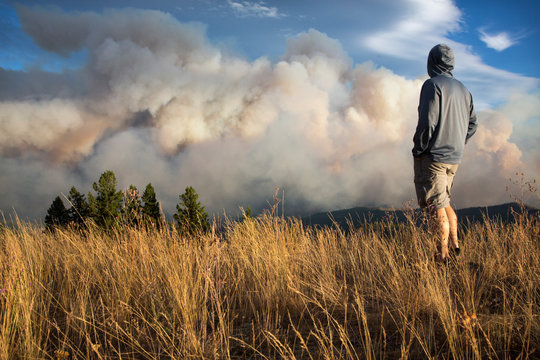 Man watching Lolo Peak Fire blow up in heavy winds from top of Blue Mountain near Missoula, Montana, USA