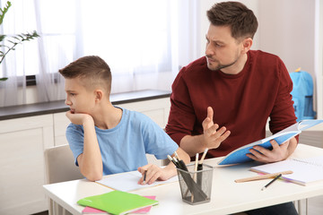Dad helping his son with difficult homework assignment in room