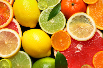 Fototapeta na wymiar Sliced and whole citrus fruits with leaves as background, top view