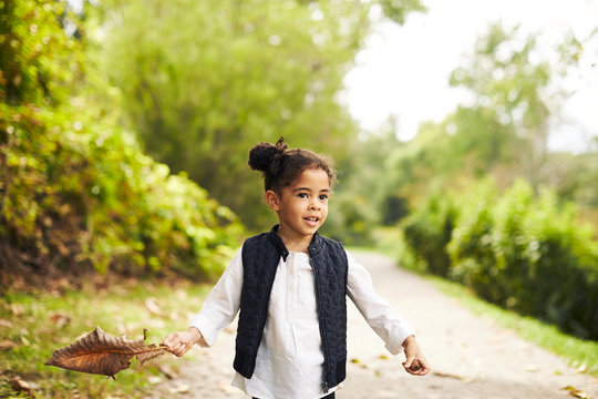 Girl with brown leaf in country road