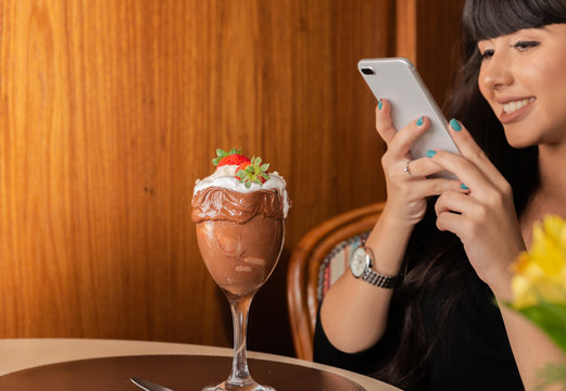 Woman taking pictures of delicious ice cream white blends strawberry with a smart phone.