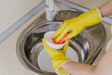 washing a white bowl with soapy suds in the kitchen sink