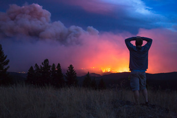 Man watching Lolo Peak fire blow up in heavy winds from top of Blue Mountain near Missoula, Montana, USA