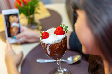 Woman taking pictures of delicious ice cream white blends strawberry with a smart phone.