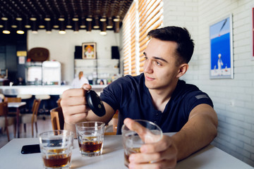 Young man drunk at bar drinking alcohol whiskey holding car keys