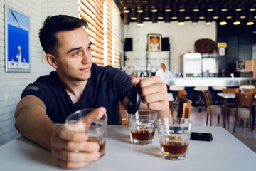 Young man drunk at bar drinking alcohol whiskey holding car keys drink and drive concept