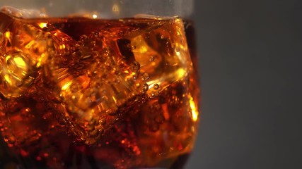 Cola in the glass with Ice cubes and bubbles rotating. Food background. Soda Close-up.