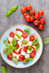 Delicious caprese salad with ripe cherry tomatoes and mini mozzarella cheese balls with fresh basil leaves.