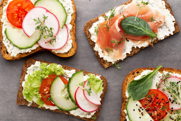 Sandwich with cereals bread and salami on dark marble background.
