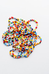 Multi coloured sand beads isolated on white background, top view with copy space