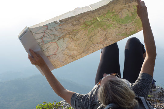Woman hiker laying on cliff edge with map