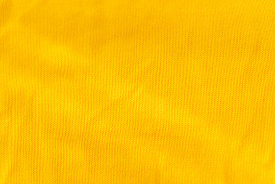Yellow crocheted fabric texture. Material is crumped a little