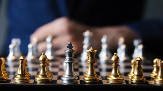 Unrecognizable male in suit making a move in chess play against gray background