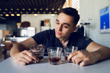 Young man drunk at pub holding glass of alcohol whiskey brandy