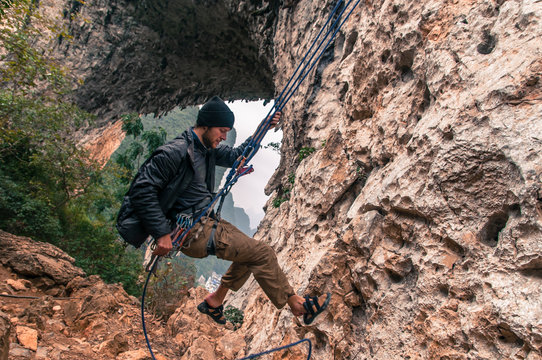 Man rappelling down from Moon Hill rock formation, Yangshuo, Guangxi Province, China
