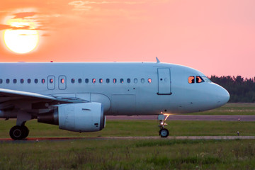Fototapeta na wymiar Close-up taxiing a white passenger airplane against the setting sun