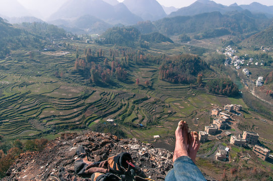 Man sitting on top of mountain after climbing it in Getu He, Guizhou Province, China