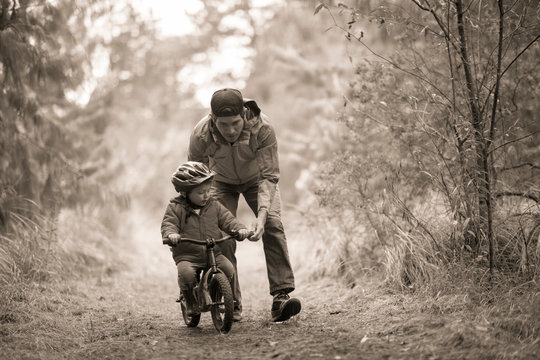 Father helping son ride small bike, Rancho Santa Elena, Hidalgo, Mexico