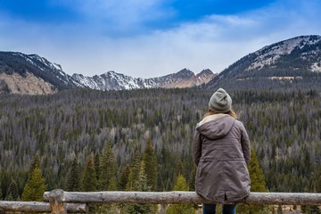 Fototapeta na wymiar Woman Sitting on Fence Viewing Rocky Mountains
