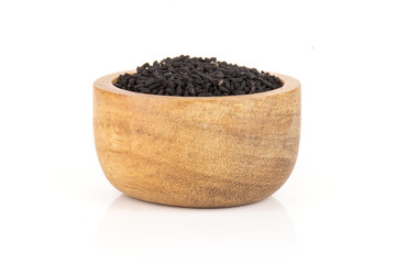 Lot of whole black cumin seeds with wooden bowl isolated on white background