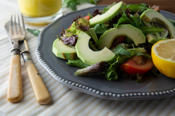 Healthy salad mix of iceberg, spinach, avocado and cucumber with olive oil, tomato and lemon.