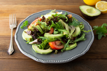 Healthy salad mix of iceberg, spinach, avocado and cucumber with olive oil, tomato and lemon.