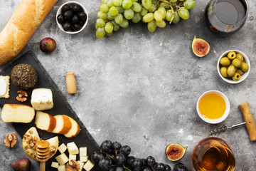 Snacks with wine - various types of cheeses, figs, nuts, honey, grapes, bread on a gray background. Top view, copy space. Food background