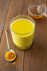 Turmeric Golden Milk. Healthy drink made with turmeric and honey. Remedy for many diseases. Rustic wooden background.