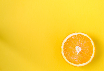 Half of orange isolated on a yellow background, top view