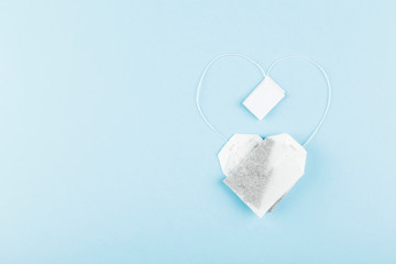 Tea bags in form of heart on blue background. Top view, copy space. Food background