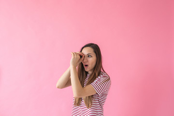 Beautiful young girl looks into a telescope made from her hands. The concept of new knowledge,...