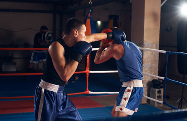 Anger man boxer exercising kickboxing with sparring partner in the ring at the sport club