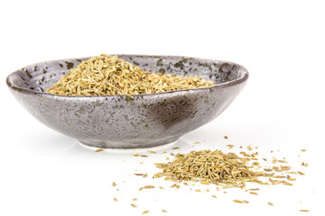 Lot of whole dry roman caraway seeds in a grey ceramic bowl isolated on white background