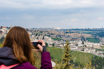 Naklejka premium Woman taking photograph with smartphone at enjoying view of Jerusalem Photograph on the phone Old City of Jerusalem.