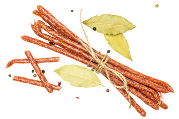 Fototapeta premium Group of lot of whole three pieces of spicy salami stick tyrolini tied by jute with bay leaf and black pepper flatlay isolated on white background
