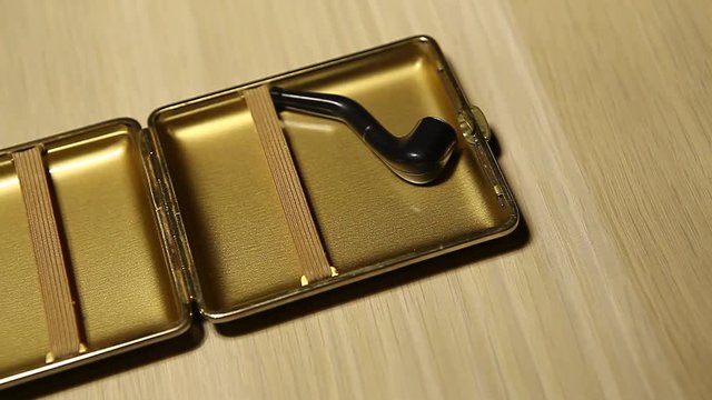 gold cigarette case smoking pipe wooden table nobody hd footage 