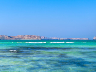 Brilliant azure blue water and rocky islands in the background