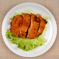 Fried meat cutlet in breadcrumbs sliced and green leaf lettuce.