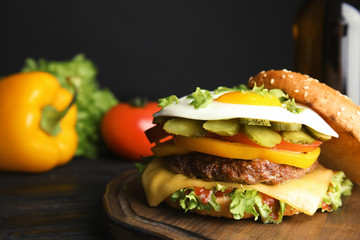 Tasty burger with fried egg on wooden board, space for text
