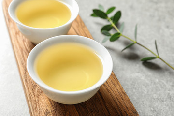 Stand with cups of freshly brewed oolong tea on grey table, space for text