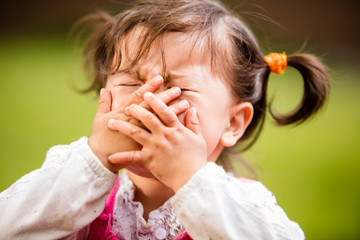 Baby girl playing and putting hands over face