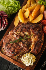 Ribeye steak with potatoes, onions and baked cherry tomatoes. Juicy steak with flavored butter