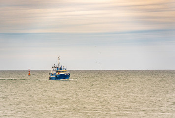 Small single fishing boat at the open sea with scenic sky.