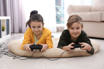 Cute children playing video games on floor at home © New Africa