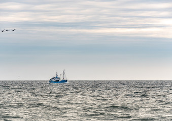 Fototapeta premium Small single fishing boat at the open sea with scenic sky.